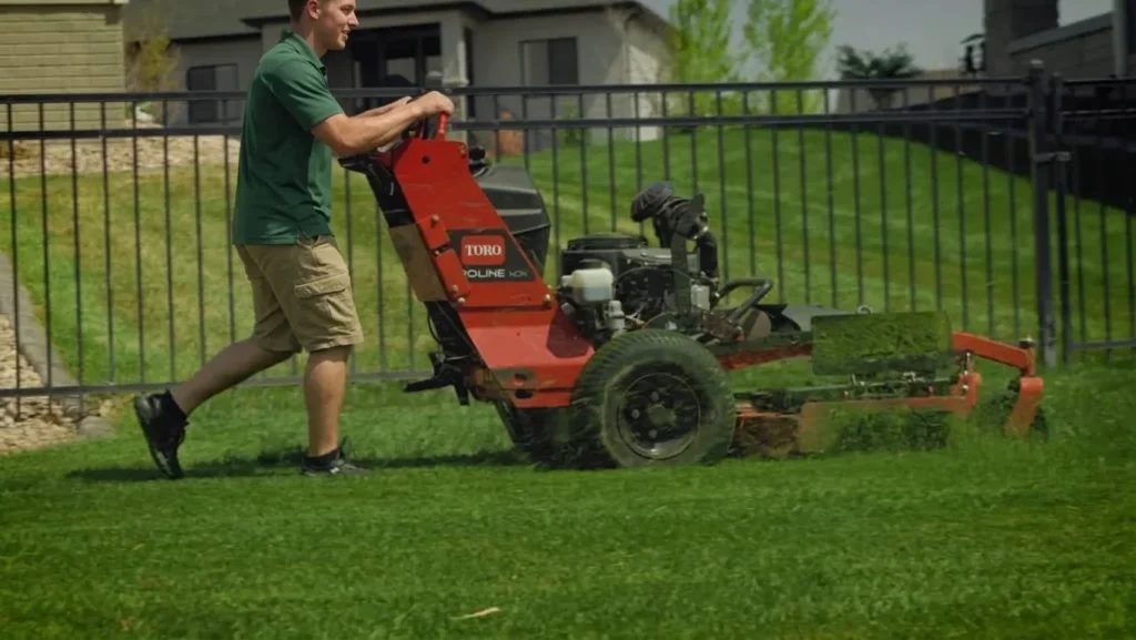 Crew member mowing at the correct height on a sloped Lincoln lawn