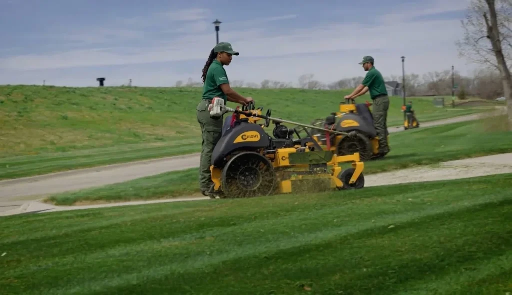 Two-person crew mowing a commercial hillside lawn together